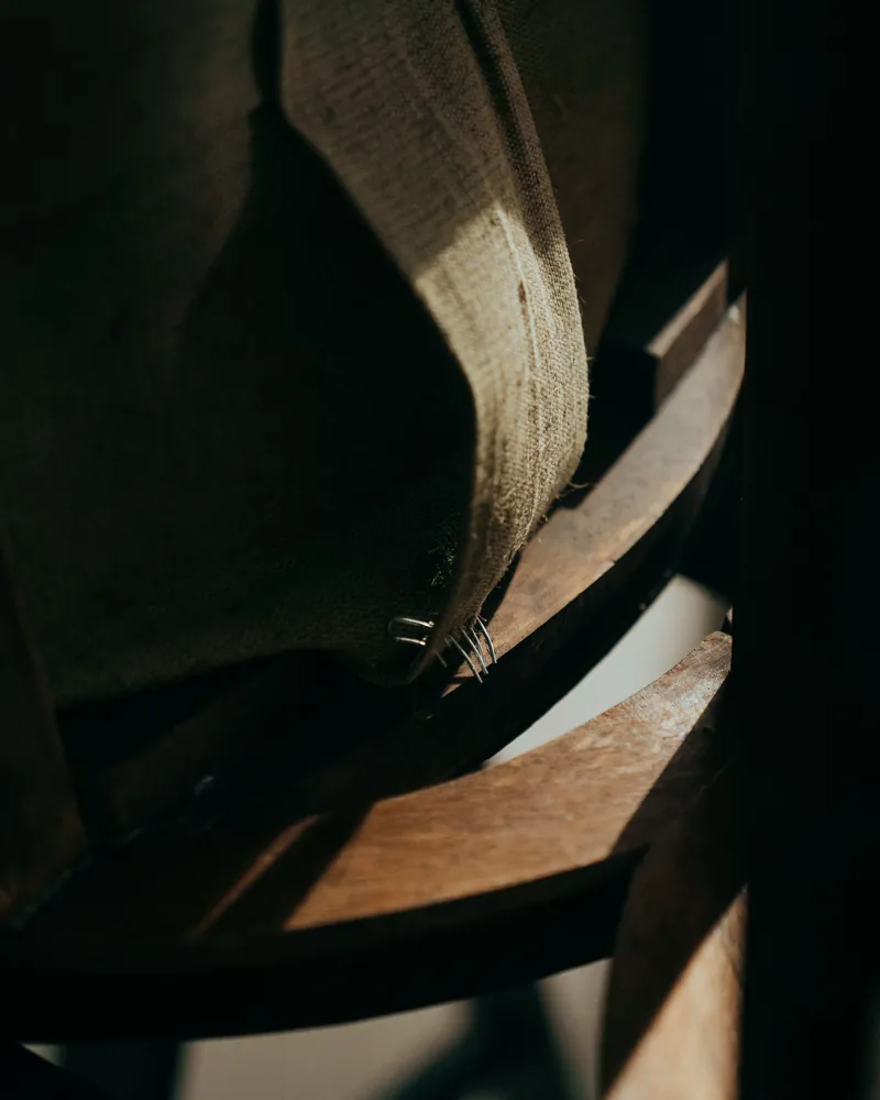 Detalle de una silla antigua en restauración con la madera y la tela a la vista
